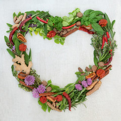 Heart shaped herb leaf and spice wreath with a selection of fresh herbs and spices with flowers on rustic white wood background with copy space.