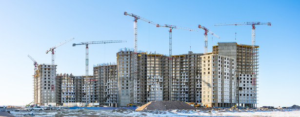 Panoramic view of the construction site with tall cranes of residential houses in the microdistricts