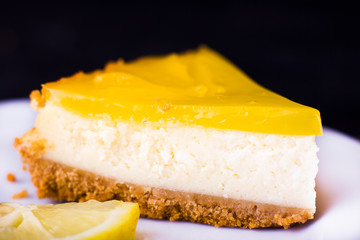Lemon cheesecake on black background decorated with lemon zest close up