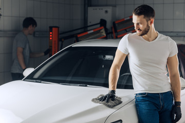 awesome handsome guy standing near the car with a rag. close up photo. copy space