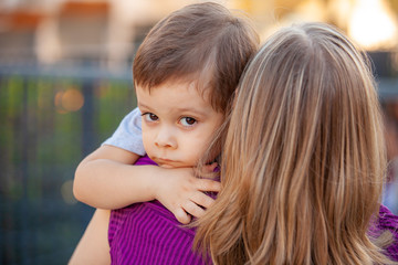 sad little boy on mother's shoulder