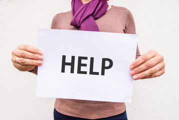 woman hands holds word HELP on paper sheet