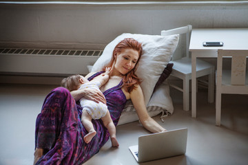 Mother hugging baby girl (6-11 months) and surfing net 