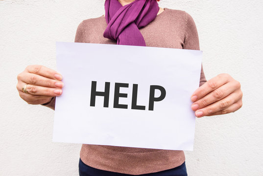 woman hands holds word HELP on paper sheet