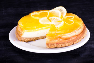 Lemon cheesecake on black background decorated with lemon zest close up