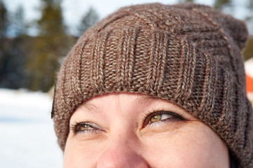 Closeup of smiling young woman wearing knit hat while looking up