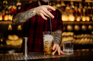 Bartender stirring a Rusty Nail cocktail with the spoon