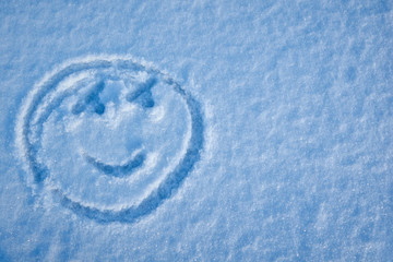 Smiley face drawing in the snow on a sunny day. copy space