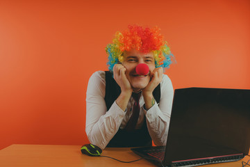 Office worker in clown wig, clown concept at work. Businessman at the computer, work on a laptop