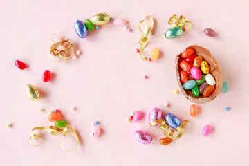 Chocolate Easter eggs and other sweets on pink background.