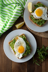 Sandwich or bread toast with avocado and a fried egg on a white plate on rustic wood table. Healthy food. Healthy eating.