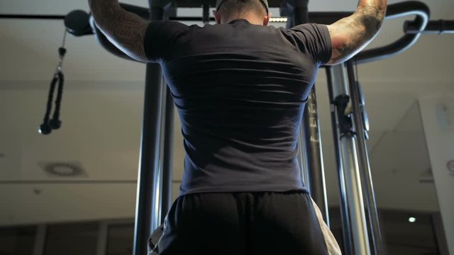 man in the gym trains the latissimus dorsi by the lat pulldown machine