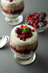 Overnight oats, muesli with berries. Healthy breakfast in glass over grey background. Tasty oatmeals with yogurt.