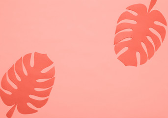 Paper cut tropical leaves in trendy coral color on pink background, top view