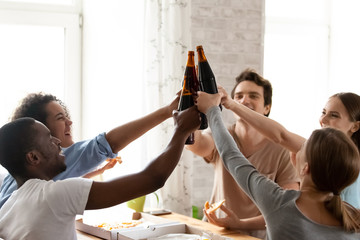 Happy multiracial people celebrate success, clinking bottles in bar