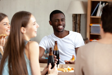 Smiling African American man drinking beer with friends in pizzeria
