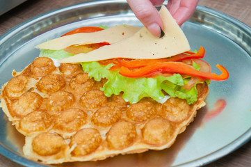 Bubble waffle, Cooking Thai, Hongkong waffles with tomatoes, lettuce, cheese and red sweet peppers. Fast food concept, fast food, restaurant