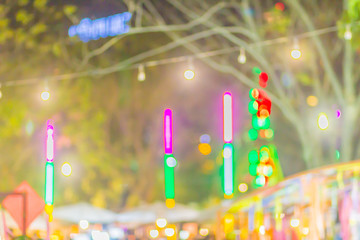 Thai temple fair with colorful decoration in blurred background. Abstract blurred focus with bokeh of night market during new year festival in the temple.