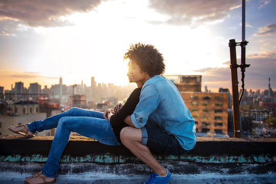 Side view of young couple embracing on rooftop during sunset