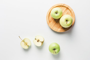 green apples on wooden stand on white background