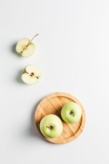 green apples on wooden stand on white background