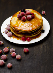 pancakes with jam and berries on wooden black background 