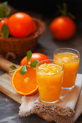 Glass of fresh orange juice with oranges on the table