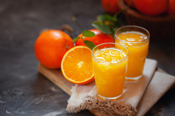 Glass of fresh orange juice with oranges on the table