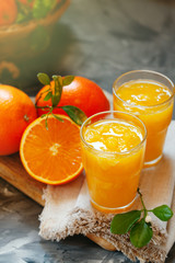 Glass of fresh orange juice with oranges on the table