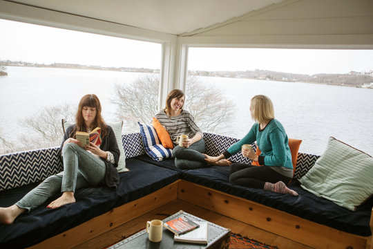 Mid adult women drinking tea reading and talking 