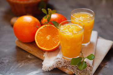Glass of fresh orange juice with oranges on the table