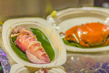 Grilled squid and crab for sale at the seafood market. Seafood barbecue with squid calamari and crab are ready to eat and bring back home. BBQ concept, selective focus.