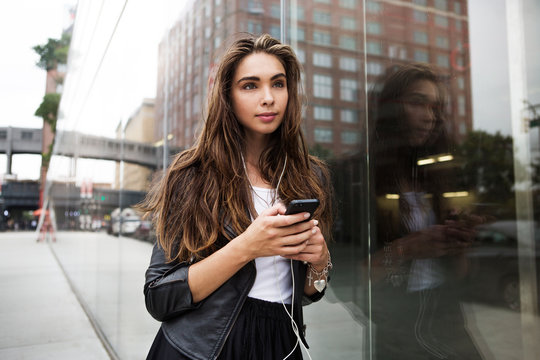 Young woman with mobile phone standing on street 