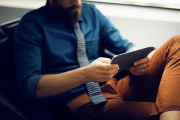 Man sitting in armchair and using digital tablet 