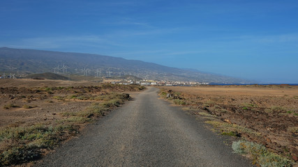 Empty road cutting through the arid volcanic lanscape of Tenerife island, road from Faro Punta de Abona towards the village Poris de Abona, concept for going the extra mile or clear work and lifestyle