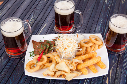 snack for beer from cheese sticks, chechel, onions and loaves of beer on the table