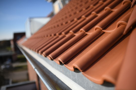 rote Dachziegel und Dachrinnen Konstruktion vom hergestellt vom Dachdecker Handwerker am Haus Geb&auml;ude ohne Wasser in der Traufe