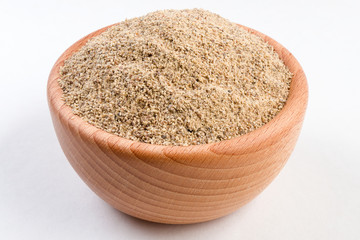 ground white pepper in wooden bowl isolated on white background.