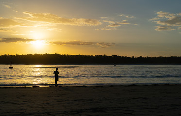 Distant silhouette of fisherman casting into Tauranga Harbour entrance,