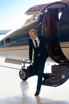 Portrait Of Businessman Stepping Off Boarding Stairs Of Private Plane 