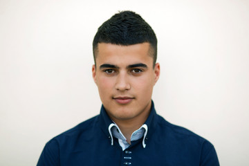 Portrait of young man with black hair in navy blue shirt 