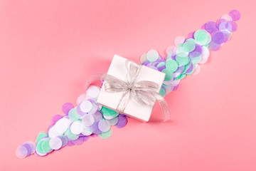 Gift box on pink background with confetti.