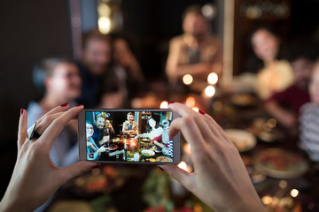 Woman's hands taking photo of friends dining 