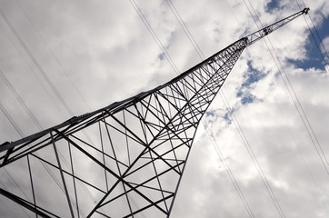 Bottom View of an electricity pylon against blue cloudy sky.