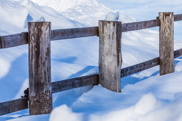 The fence or the hedge and the heaps of snow in the countryside or in the village in the cold and...