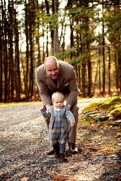 Father teaching son (12-17 months) to walk 