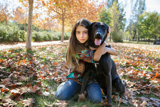 Girl kneeling and hugging dog in park 