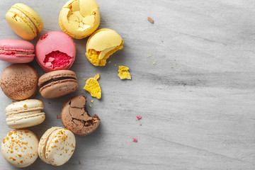 French macarons scattered over wooden background