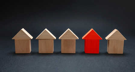 Red house model among wooden houses, black color background