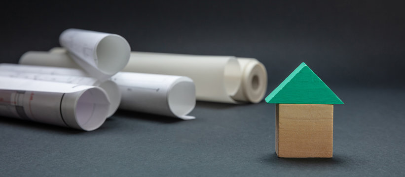 Small house with roof model and project blueprints on black color background